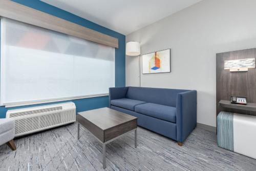 a living room with a blue couch and a table at Holiday Inn Express & Suites Austin Airport East by IHG in Austin