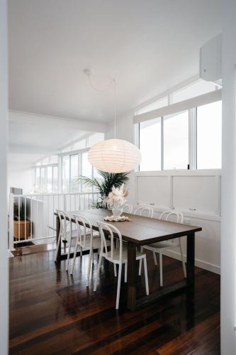a dining room table with white chairs and a large light fixture at Palm Springs Retreat in The Range