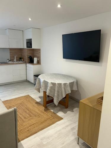 un salon avec une table et une télévision au mur dans l'établissement Cozy studio Carnon Plage, à Mauguio