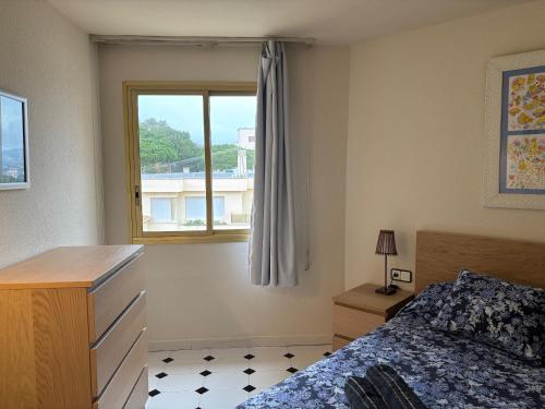 una camera da letto con un letto e una finestra di Precioso apartamento en S'Agaró con fantásticas vistas al mar a Sant Feliu de Guíxols