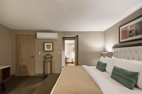 a bedroom with a large white bed and a door at Dominion Polanco in Mexico City