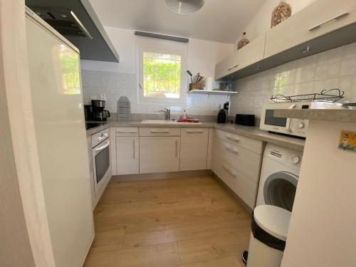 une cuisine blanche avec un évier et un lave-vaisselle dans l'établissement Maison vue mer Palombaggia, à Porto-Vecchio