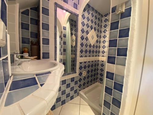 une salle de bain carrelée bleue avec un lavabo et une douche dans l'établissement Maison vue mer Palombaggia, à Porto-Vecchio