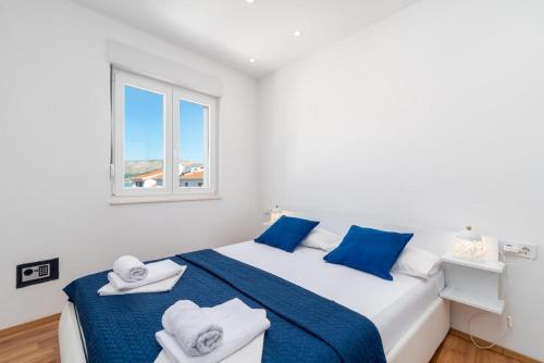 a white bedroom with blue and white towels on a bed at Apartmani Marko in Trogir