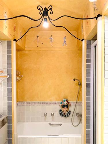 La salle de bains est pourvue d'une baignoire avec des figurines sur le mur. dans l'établissement Appartamento in Saint Tropez centro di 2 locali con aria condizionata Wi-Fi e disponibilità parcheggio, à Saint-Tropez