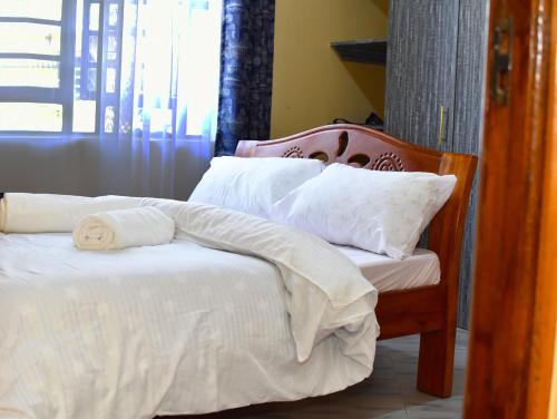 a bed with white sheets and pillows in a room at MG's Bamboo Shade Villa, Karatina in Gathehu