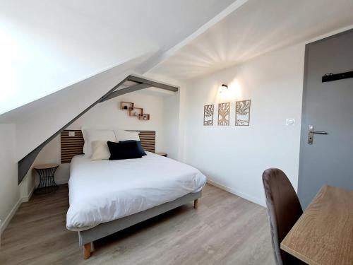 a bedroom with a white bed and a table at L'Attique, confort, aéré, centre-ville, Netflix in Laval