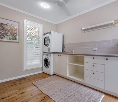 una cocina con refrigerador y lavadora y secadora en Lamington Cottage, en The Range