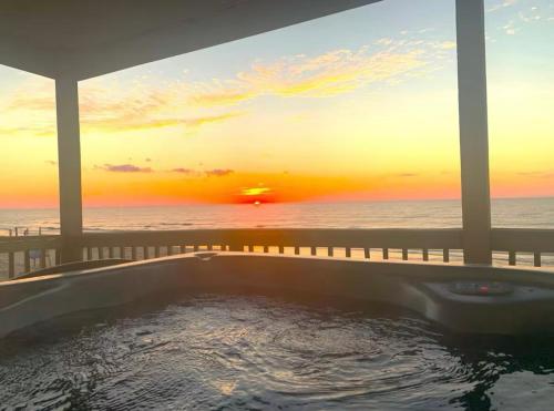 a hot tub with a view of the ocean at sunset at Starfish Beachfront Swim-Up in Surfside Beach