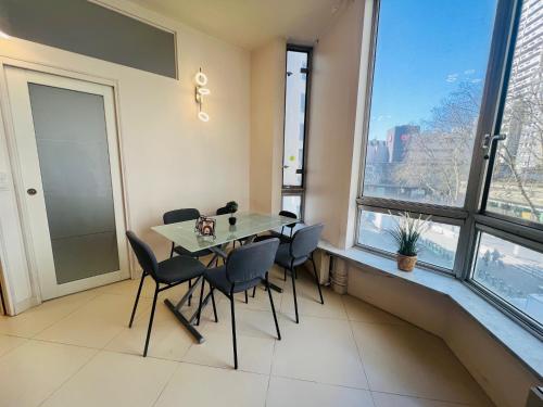 une salle à manger avec une table, des chaises et des fenêtres dans l'établissement Appartement Tour Eiffel Beaugrenelle Paris, à Paris