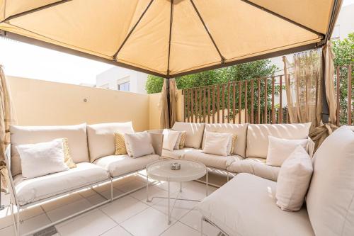 a patio with white couches and a large umbrella at Bright and Airy 2BR, Family-Friendly with Pool and Gym in Dubai