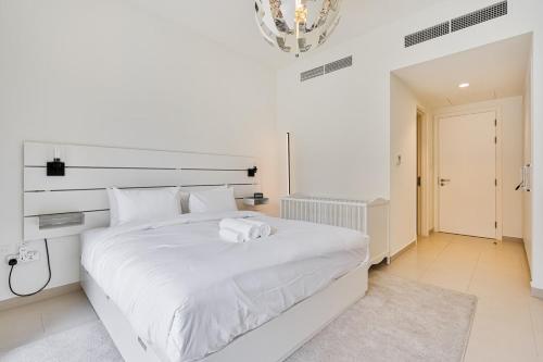 a white bedroom with a large bed with white sheets at Bright and Airy 2BR, Family-Friendly with Pool and Gym in Dubai