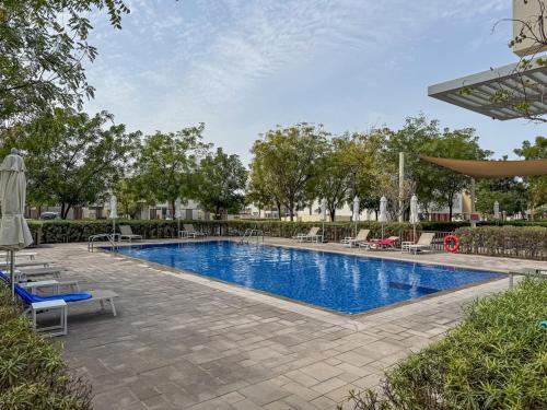 a swimming pool with chairs and umbrellas at Bright and Airy 2BR, Family-Friendly with Pool and Gym in Dubai