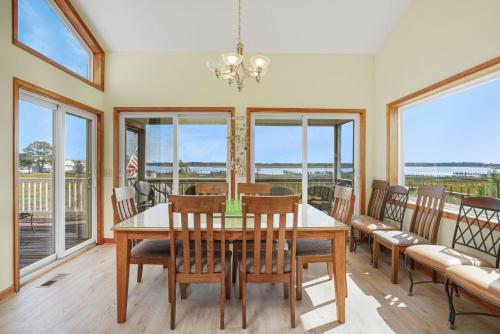 a dining room with a table and chairs and windows at Return - Waterfront with boat dock! in Black Point Landing