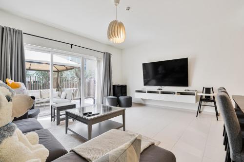 a living room with a couch and a tv at Bright and Airy 2BR, Family-Friendly with Pool and Gym in Dubai