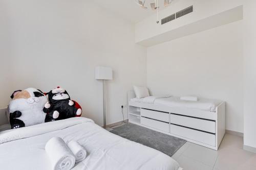 a white bedroom with a bed and a dresser at Bright and Airy 2BR, Family-Friendly with Pool and Gym in Dubai