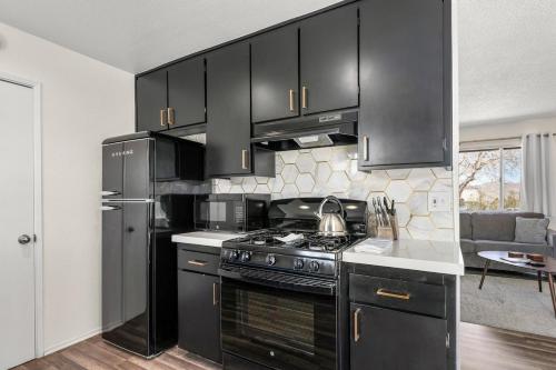 a kitchen with black cabinets and a stove top oven at Grand Desert Oasis - SPA - A Location - JT Park in Joshua Tree