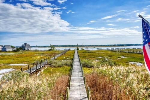 a wooden boardwalk through a marsh with an american flag at Return - Waterfront with boat dock! in Black Point Landing