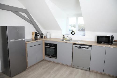 a kitchen with white cabinets and stainless steel appliances at L'Attique, confort, aéré, centre-ville, Netflix in Laval