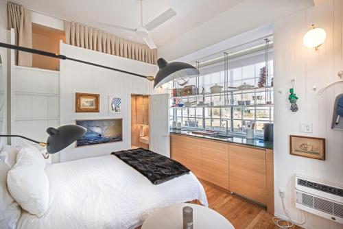 a bedroom with a white bed and a kitchen at Renovated, Modern Downtown Loft in Provincetown