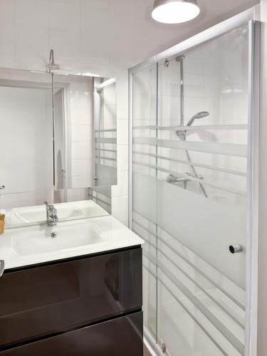 une salle de bain blanche avec un lavabo et une douche dans l'établissement Le petit Volcan d'Aurillac - centre ville - 2 pers, à Aurillac