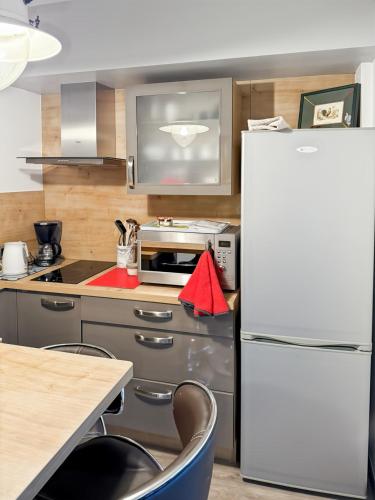 une cuisine avec un réfrigérateur blanc et une table dans l'établissement Le petit Volcan d'Aurillac - centre ville - 2 pers, à Aurillac