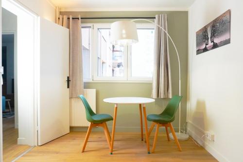 une salle à manger avec une table et deux chaises vertes dans l'établissement Appartement cosy T3 - RER C 400m, à Choisy-le-Roi
