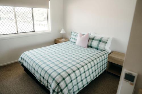 a bedroom with a bed with a plaid blanket and a window at Unit 4, Rocky CBD in Rockhampton