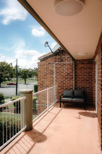 a balcony with a black couch on a brick wall at Unit 4, Rocky CBD in Rockhampton