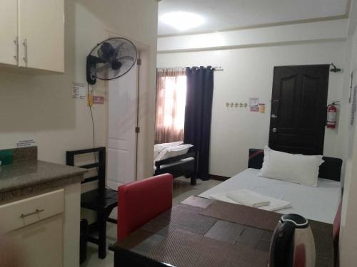 a small room with a bed and a table and a kitchen at V.F. Riton Apartelle in Laoag