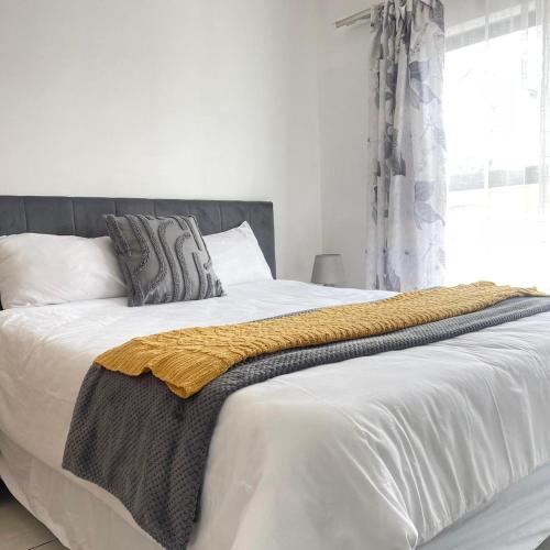 a bed with a yellow blanket on top of it at Joy Apartment@The Blyde in Pretoria