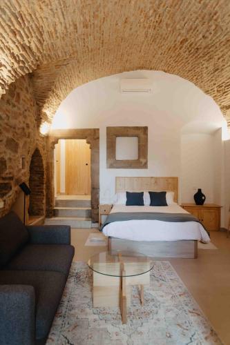 a bedroom with a bed and a couch and a table at PORTAL DE SANTIAGO in Cáceres