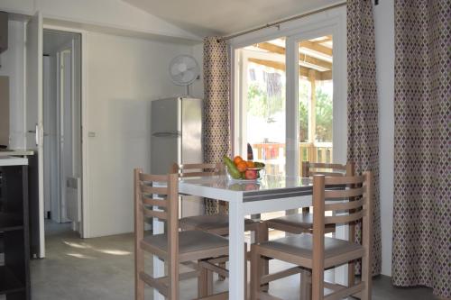 une cuisine avec une table et des chaises blanches ainsi qu'une fenêtre dans l'établissement Mobile home - Bonne Anse La Palmyre - 8 pers, aux Mathes