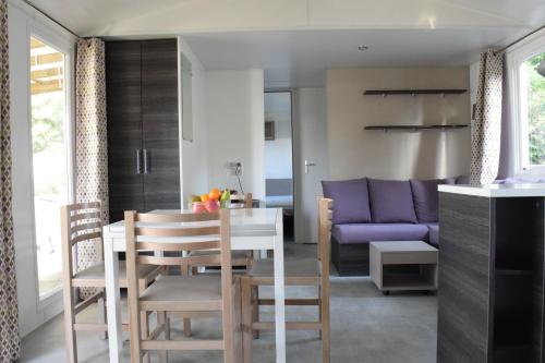 Una cocina y una sala de estar con una mesa y un sofá morado. en Mobile home - Bonne Anse La Palmyre - 8 pers, en Les Mathes