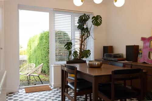 a dining room with a table and chairs and a window at Cosy mid century Stockport with views, dog walks, woodburner in Woodley