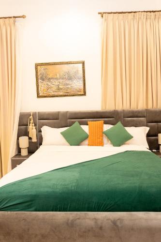 Una cama grande con almohadas verdes y naranjas. en De Cove, en Ogbojo