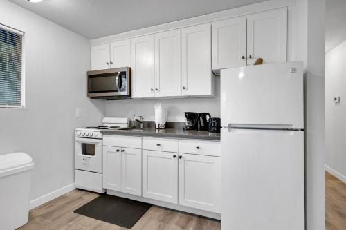 a white kitchen with white cabinets and a refrigerator at Rainier Entire Upper Floor - Walk to Metro in Seattle