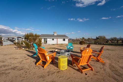 a group of chairs sitting around a fire in the sand at Maison YV - Fire-pit - Desert Beauty - A Location in Yucca Valley