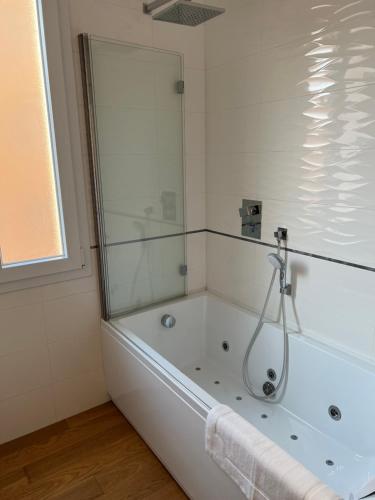 a white bathroom with a tub with a shower at Appartamento Liguria5 in Bologna