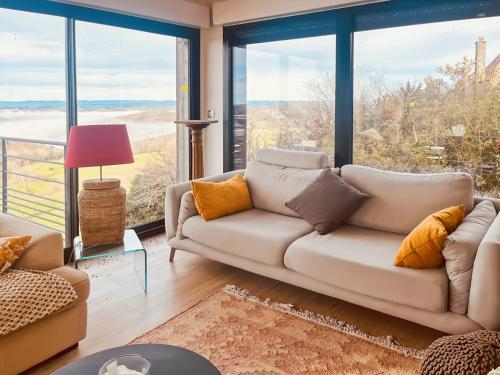 a living room with a couch and large windows at S'évader vers l'horizon 6pers, calme, wifi in Chalvignac