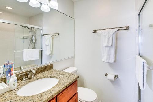 Un baño con lavabo, inodoro y espejo. en Walk to Ocean Family Retreat in Ormond Beach!, en Ormond Beach
