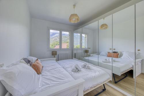 - une chambre blanche avec 2 lits et un miroir dans l'établissement Les jardins de Duingt, à Duingt