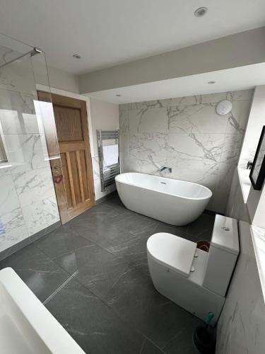 a bathroom with a tub and a toilet and a sink at Prior House Farm in Berwick-Upon-Tweed