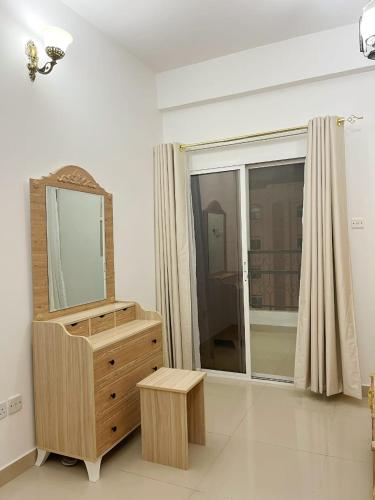 Un baño con una cómoda con espejo y una ventana. en درة الغبره, en Mascate