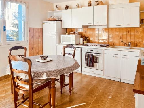 une cuisine avec des armoires blanches et une table et des chaises dans l'établissement Le gîte de Jeannette, 8pers, à Lacapelle-Viescamp
