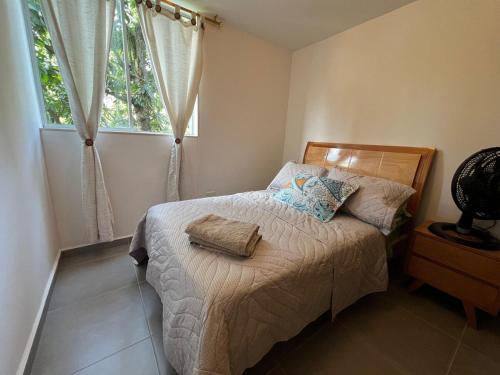Un dormitorio pequeño con una cama con ventana. en Apartamento Portanova, vista al bosque, en Piedecuesta