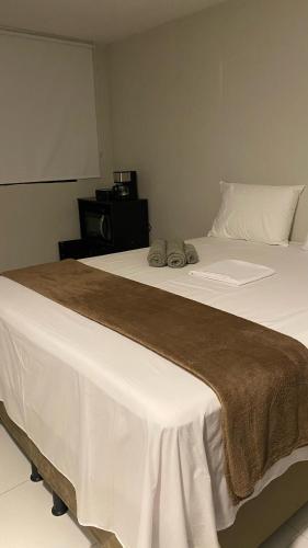 a bedroom with two beds with white sheets and brown blanket at Aloha Noronha Suites in Fernando de Noronha