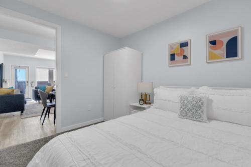 a white bedroom with a bed and a living room at You will love this 2BR Guest Suite in SE Calgary in Calgary