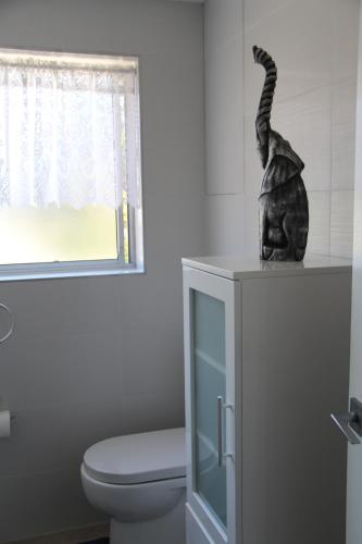 a bathroom with a toilet and a statue of a cat on a counter at Beaches Serviced Apartments in Nelson Bay
