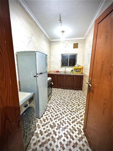 a kitchen with a refrigerator and a tile floor at White Apartment in Aqaba